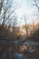 Young man in an orange jacket relaxes in the flow of a river in the Wallonia region of Belgium. Reflection of a man in the river