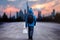 Young man with a outdoor jacket walking towards a city sundown