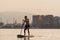 Young man paddle surfs in the mediterranean sea at sunset.