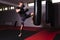 Young man is participating in a workout, practicing his boxing skills by performing a powerful kick