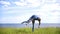 Young man performs acrobatic stunts on the hill on background of river