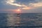 A young man performs a somersault in the sea at sunset