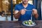 Young man photographing his salad at a bistro table