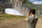 Young man photographing the water outlet of a dam