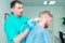 Young man at the physiotherapy receiving laser therapy massage. A chiropractor treats patient`s cervical spine in medical office.