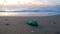 Young man pick up plastic bottle from sea shore on sunset time,pollution concept