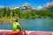 Young man at pier mountain lake with high peaks