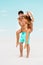 Young man piggybacking girlfriend on sandy beach