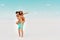 Young man piggybacking girlfriend while woman pointing with finger away on sandy beach