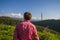 Young man in pink shirt from back enjoying beautiful mountain vi