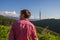 Young man in pink shirt from back enjoying beautiful mountain vi