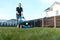 Young man in a plaid shirt and jeans mows lawn