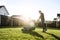 Young man in a plaid shirt and jeans mows lawn