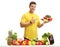 Young man with a plate pointing behind a table with fruit and vegetables