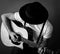 Young man playing an acoustic guitar. Selective focus. B&W