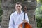 Young man playing cello outside. Cellist playing classical music on cello