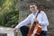 Young man playing cello outside. Cellist playing classical music on cello