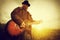 Young man playing on the guitar outdoors. Vintage