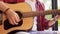 Young man playing guitar sitting on windowsill