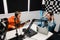 Young man playing guitar while woman recording podcast in radio studio