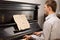 Young man playing music on a wooden piano