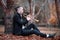 Young man plays golden trumpet in gloomy autumn park