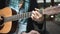 The young man plays hands and on a classic acoustic wooden guitar on the street