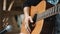 The young man plays hands and on a classic acoustic wooden guitar on the street