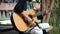 The young man plays hands and on a classic acoustic wooden guitar on the street