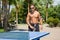 A young man plays table tennis without shirts in a park on a background of palms in a city in the summer.