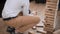 A young man plays wooden block tower board game at business meeting