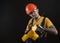 A young man posing on a black background in a work uniform and a construction tool