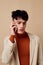 A young man posing with a phone in his hands in a jacket elegant style model studio