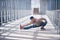 Young man practices yoga asana indoors in the empty covered footbridge