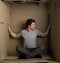 Young man is pressuring on walls inside cardboard box