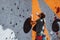 Young man professional climber assists someone on climbing wall at training center in sunny day, outdoors. Concept of