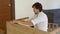 A young man professional furniture assembler assembles a wooden table in a kitchen