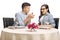 Young man proposing to a young woman with a ring at a restaurant table