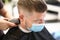 Young man in protective mask on face makes haircut in beauty salon portrait