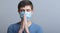 Young man in a protective medical mask praying to God for help and support in difficult times for mankind, doctor on studio