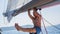 Young man pulled on the hand on the mast of a sailing yacht. Sport.