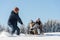 Young man pulling girls on winter sledge