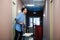 Young man pushing a housekeeping cart laden with clean towels, laundry and cleaning equipment in a hotel as he services