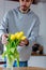 Young man put in yellow tulips in glass