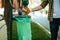 Young man puts garbage in plastic bag in park