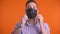 Young man putting black face mask and giving thumbs up, studio shot