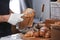 Young man putting croissant in paper bag with tongs in bakery