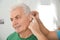 Young man putting hearing aid in father`s ear