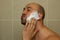 Young man putting shaving cream on his face