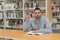 Young man with raised finger surprised that he has found the solution with a book on the table in the library